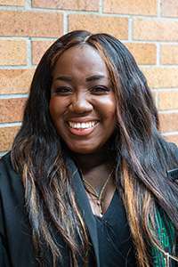 Maame Efua DeHeer smiling and wearing academic robes.