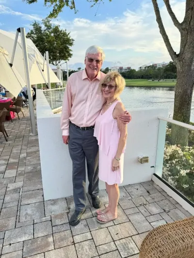 Brian and his wife standing arm and arm on a waterfront patio