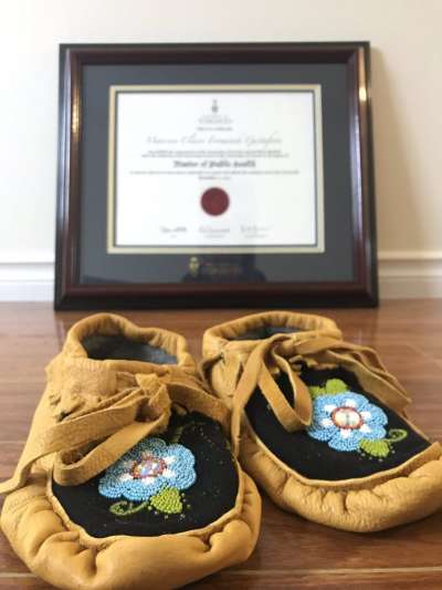 Gustafson's moccasins, beaded with a growing flower motif, sit in front of her graduation certificate.