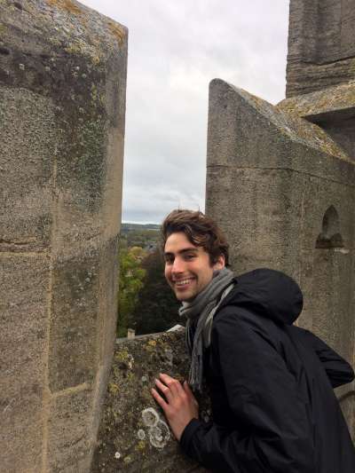 Phil Schwarz smiles as he stands on a rooftop and looks out between stone battlements.