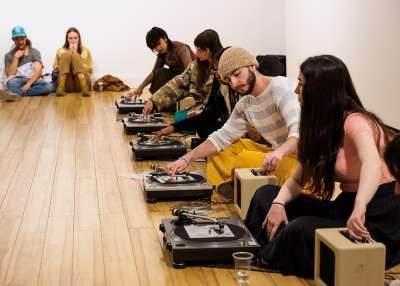 A group of people sitting on the floor with turntables