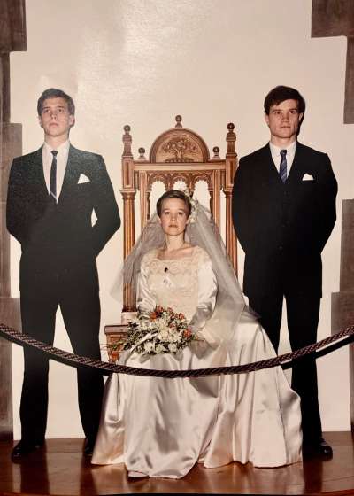 A sitting bride is flanked by two members of the bridal party