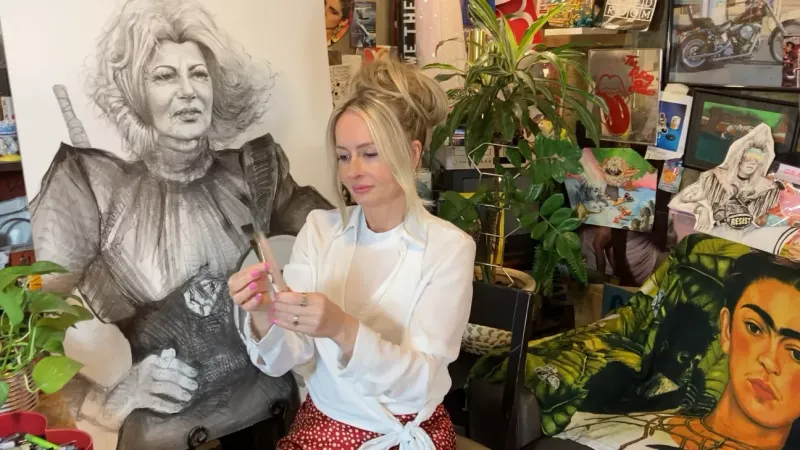 Erin Finley sits in her art studio surrounded by paintings.