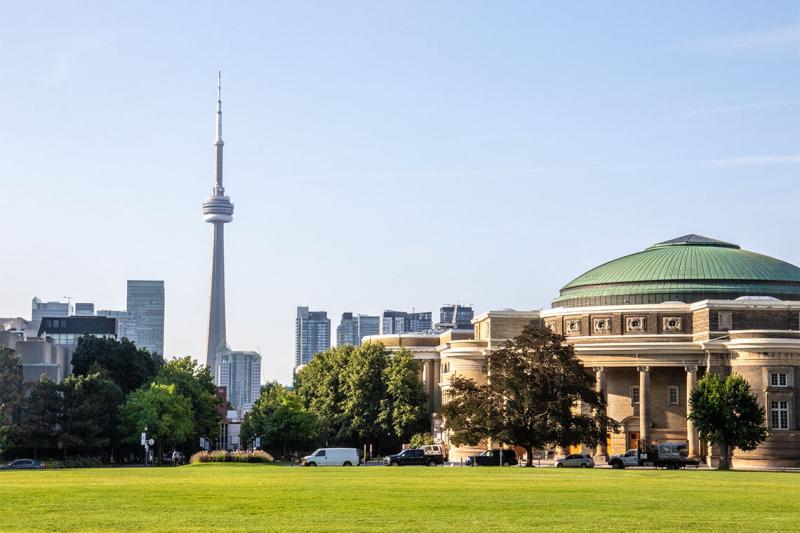 The lawn of Front Campus stretches out towards Convocation Hall, with the CN Tower in the background.
