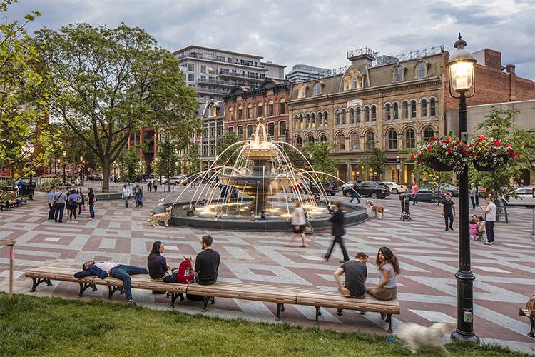People play and relax around the huge fountain in Berczy Park. The three-tier structure features 27 cast-iron dogs.