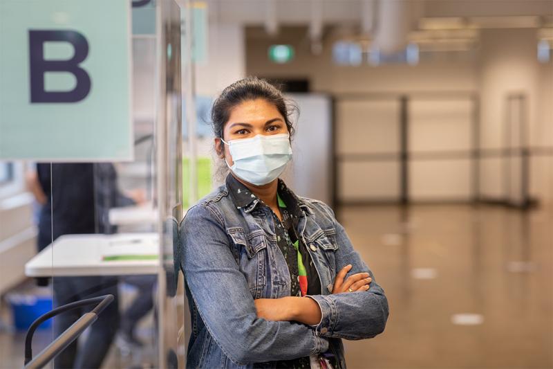 Upasana Saha, wearing a mask, stands in a hallway.