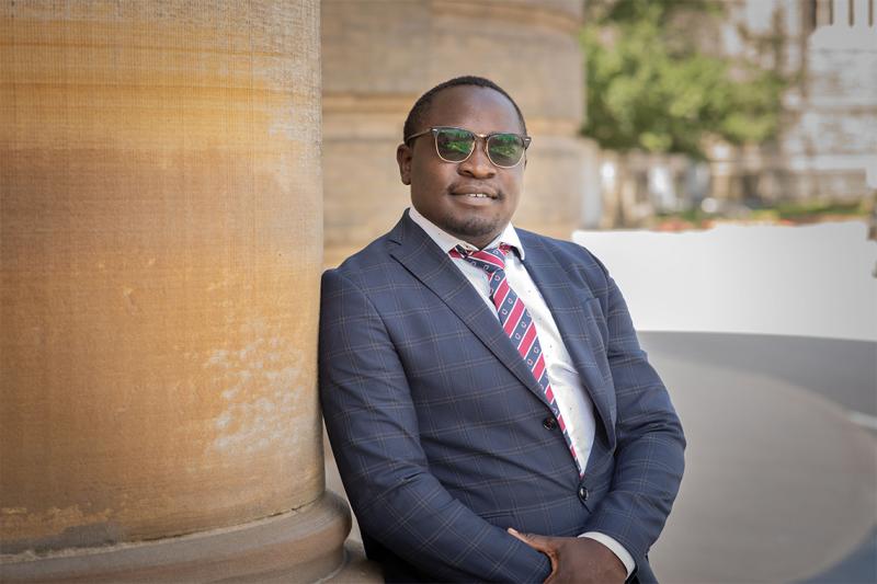 Michael Samakayi smiles as he leans on a pillar outside Convocation Hall.