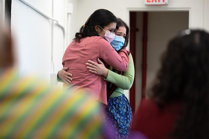 Kristine Keon and Angelique Belcourt, wearing masks, hug tearfully at the Indigenous Grad celebration.
