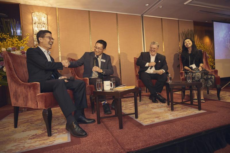 Four people sit on stage talking and laughing.
