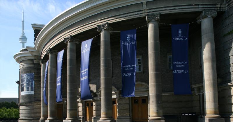 Banners hang on the pillars outside Convocation Hall. They read: Congratulations to all our graduates, University of Toronto.