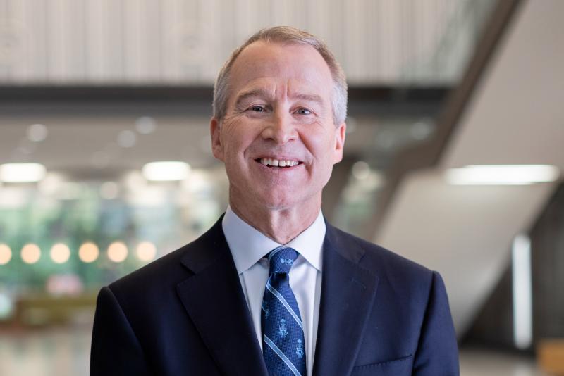 Brian Lawson smiles as he stands in the atrium of a lofty building.