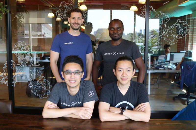 BenchSci co-founders and U of T alumni Liran Belenzon, Elvis Wianda, David Chen and Tom Leung, standing in a busy office.