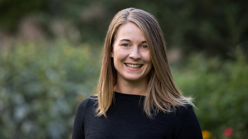 A portrait of Maaike Canrinus smiling in front of some greenery