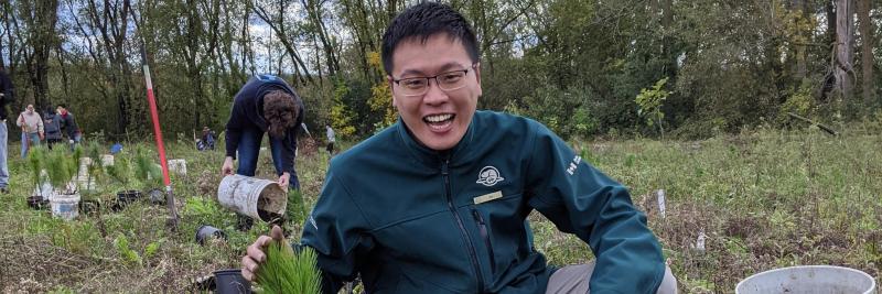 Da Chen smiles as he holds a tree seedling ready to plant.