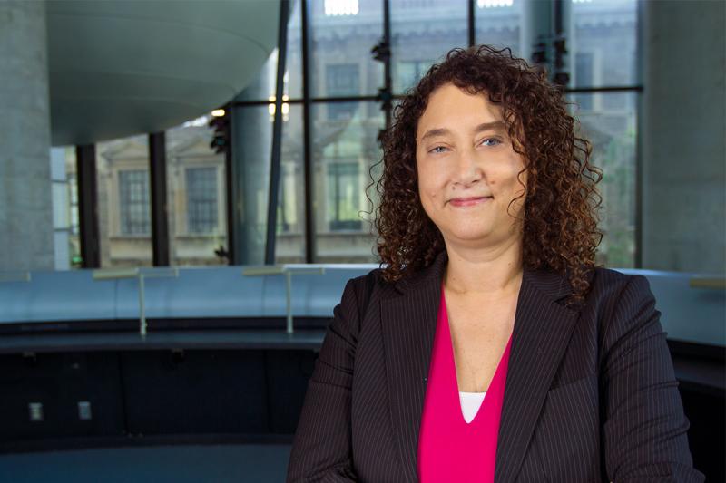 Lisa Dolovich smiling quietly in an atrium indoors.