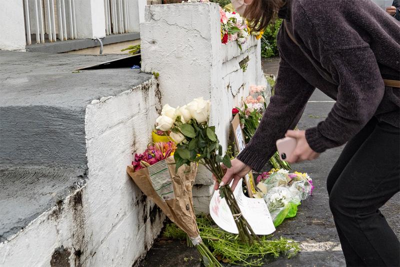 A woman reaches down to add a bunch of perfect roses to other flowers on a wall outside a spa in Atlanta.