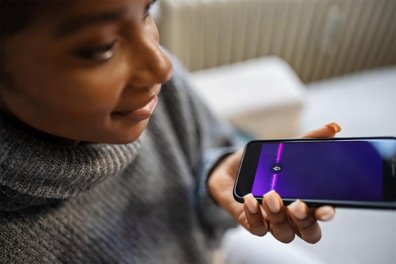 A young woman speaking into a smartphone.