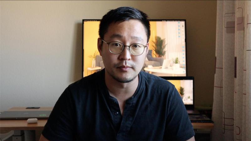 Gimmy Chu looks serious while talking on a video call in a home office.