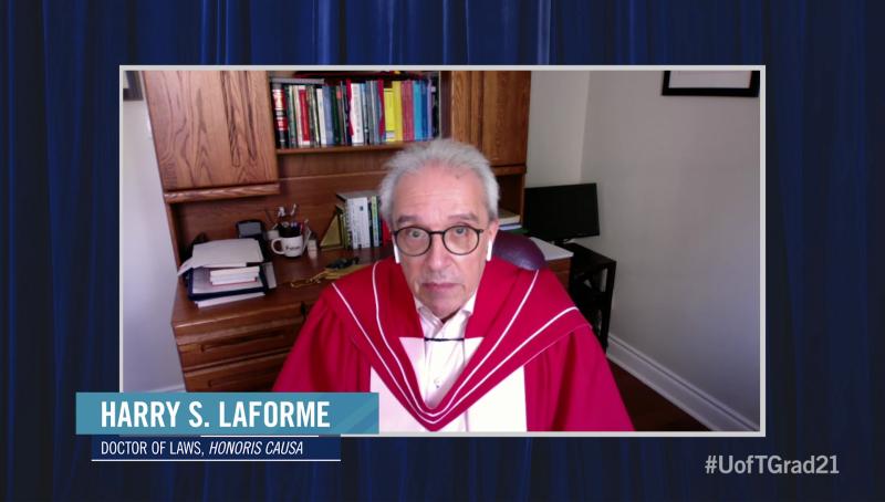 Harry LaForme, wearing his academic robes, speaks on video in front of a wooden desk and bookshelf.