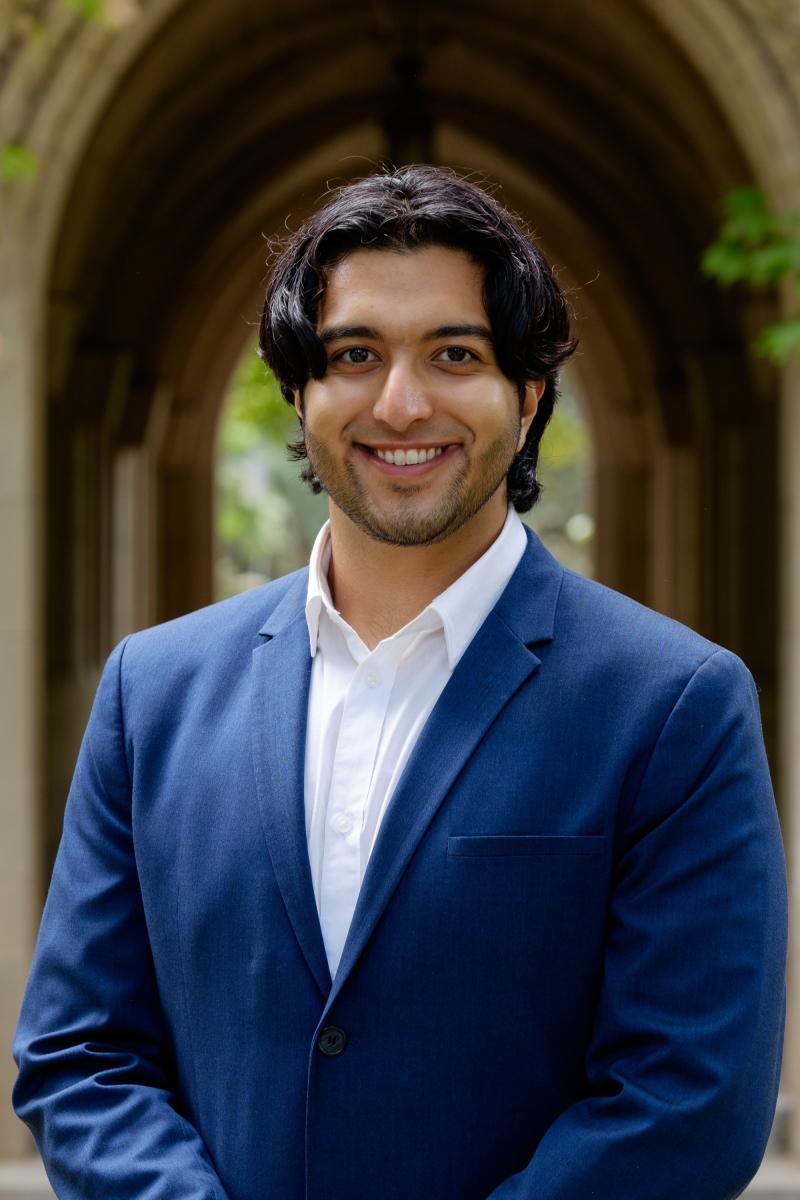 A portrait of a young person smiling and wearing a blue business suit. 