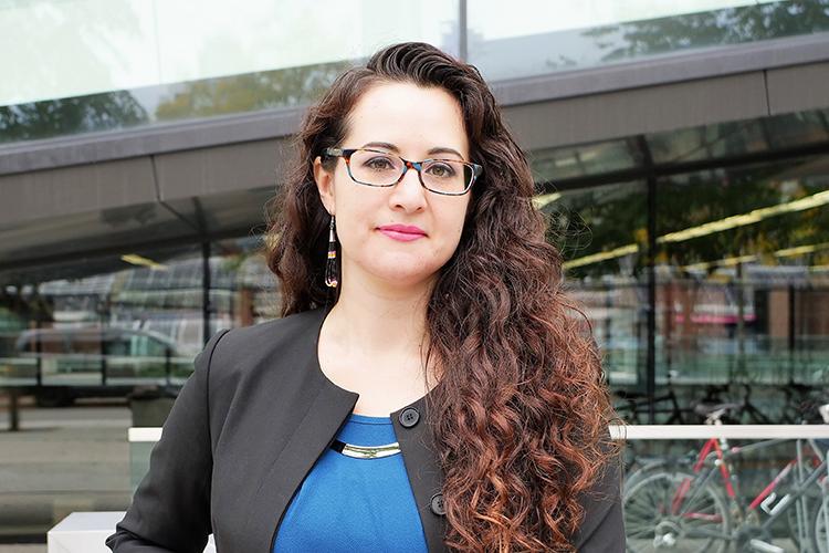 Jennifer Brant looks serious as she stands on a sidewalk in front of a building.
