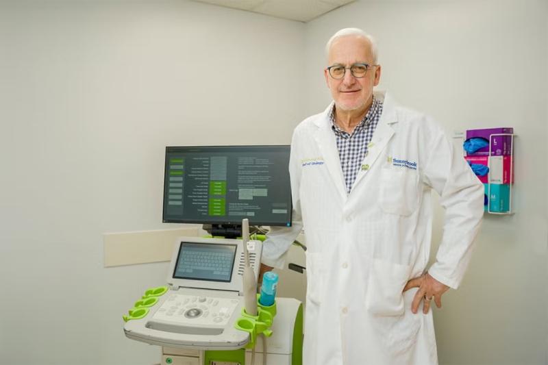 A man in a white lab coat standing next to a piece of medical equipment