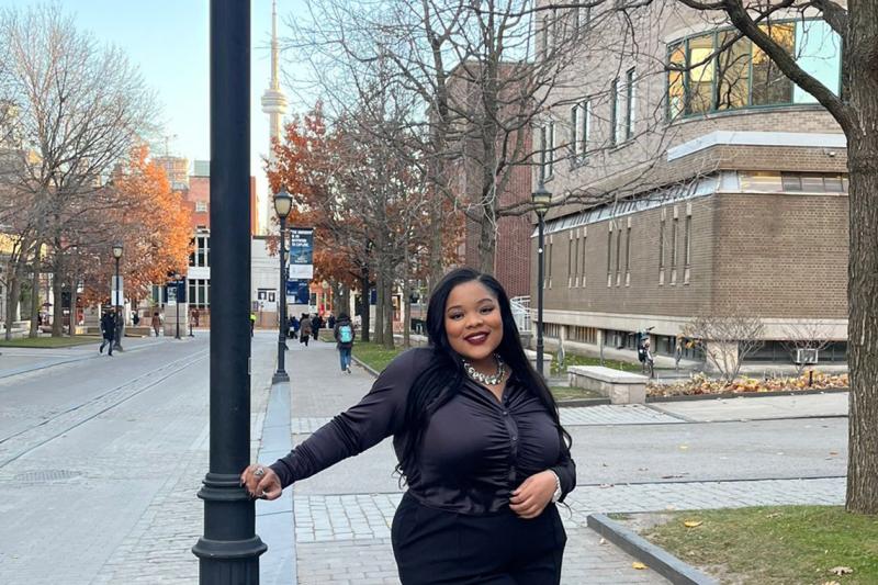 Lashae Watson smiles happily as she leans on an iron lamp post at a street corner on St. George campus.