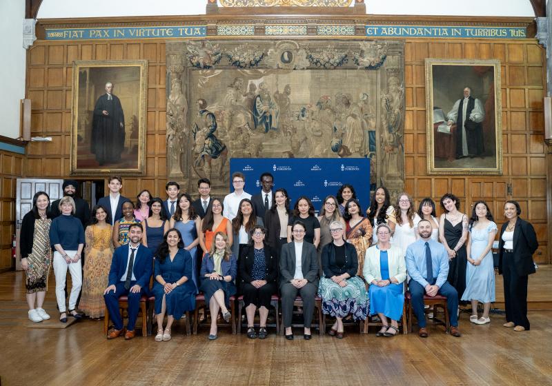 A group of people sitting and standing in a formal university hall