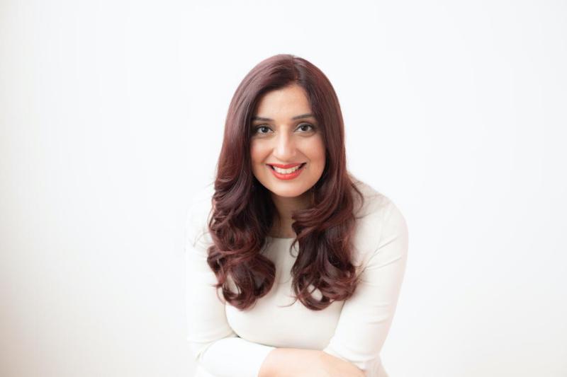 Portrait of Samra Zafar leaning forward and smiling.