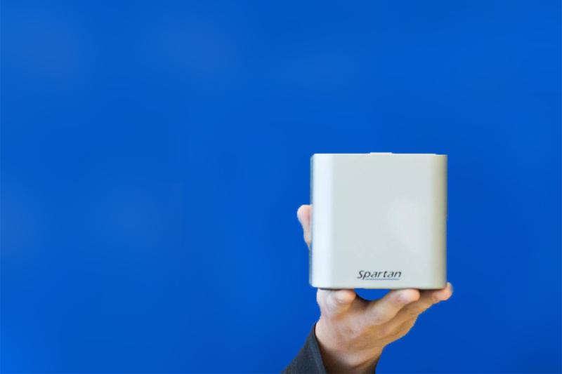 A hand holds up a smooth metal cube labelled: Spartan.