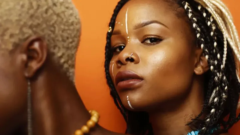 An artistic photograph of a woman with lines of white paint on her face and braids