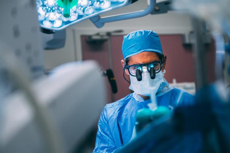 Neurosurgeon Taufik Valiante in an operating room, looking closely at a small machine