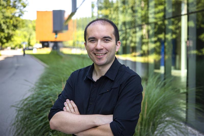 Florian Shkurti stands with arms folded on the grass outside a building.