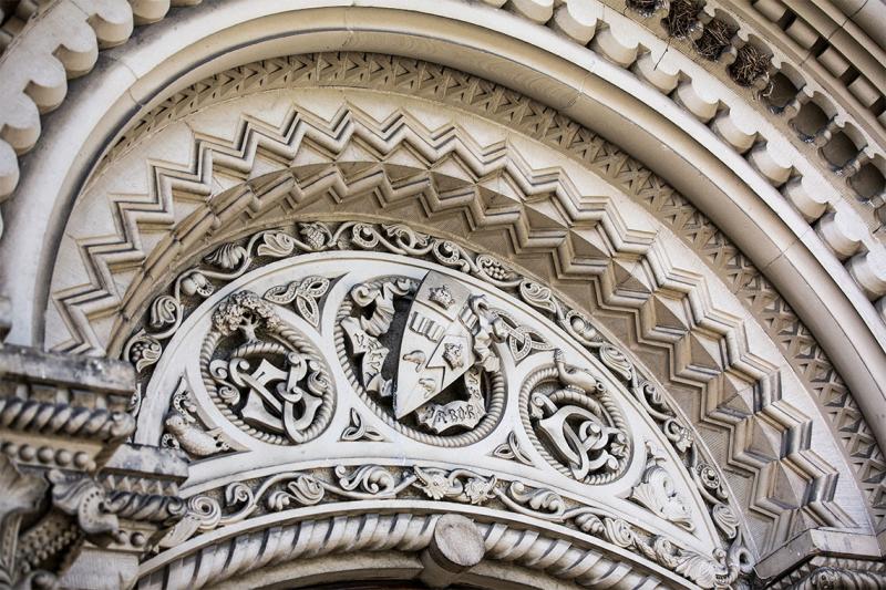 An elaborately carved stone archway with the U of T crest at the apex.