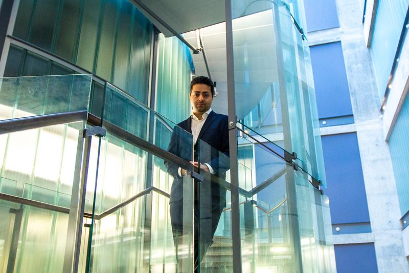 Parham Aarabi looks down from a glass-walled staircase that spirals up through an indoor courtyard.