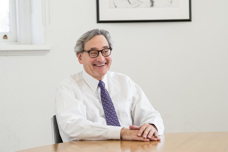 MIchael Sabia laughs while sitting with his hands folded on a desk.