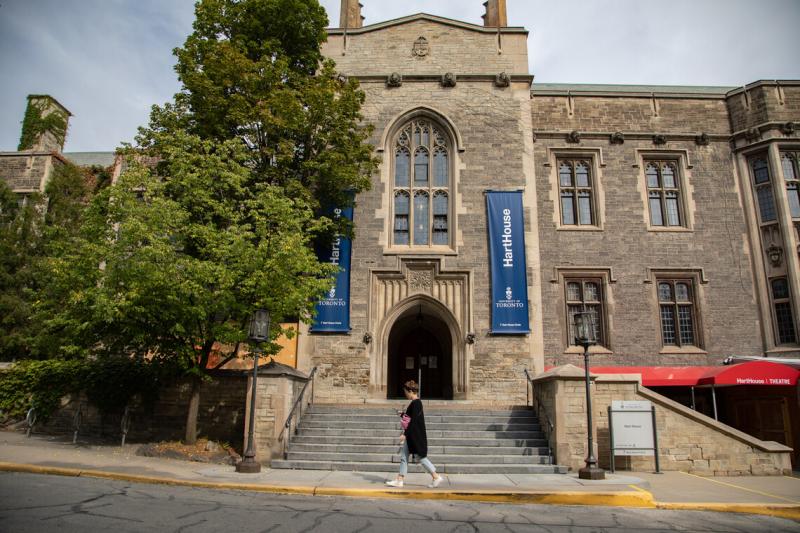 The entrance to Hart House, an old stone building with ivy on the walls, and steps going up to an arched doorway.