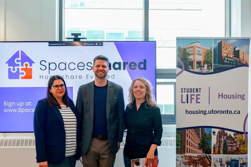 Three adults standing in front of a sign