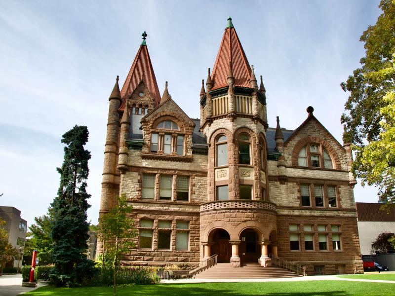 Victoria College's main building on a sunny day. The building has several elaborate turrets and spires.