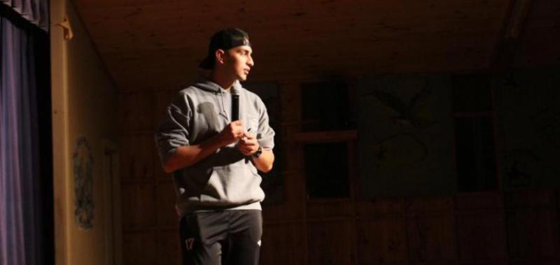 Yahya Ali stands on a stage holding a microphone.