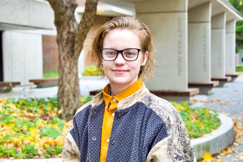 Chandler Fitzpatrick smiles while standing in front of a planter at New College Plaza.