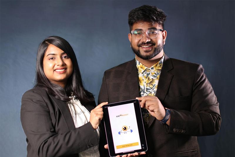 Purnashree and Pradipta Chowdhury smile and hold up a tablet that has the Eye Buddy program loaded.