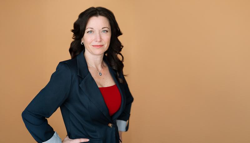 A person in a business suit posing in front of an orange background