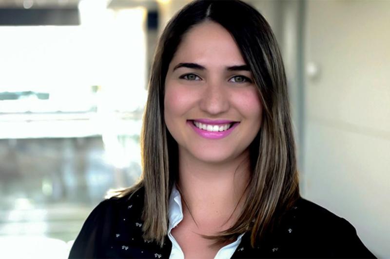 Giovanna Schver smiles while standing in a hallway indoors.