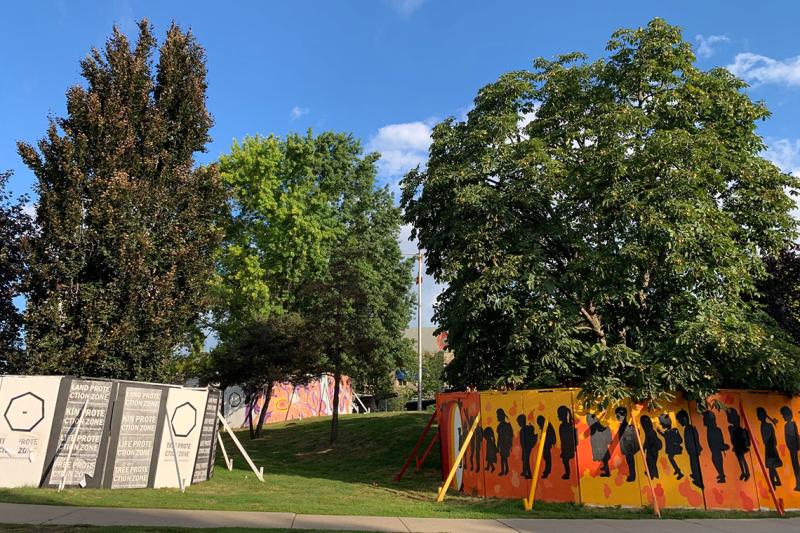 Three mature trees are surrounded by six-feet-high murals: flowers, figures of children, and the words Land Protection Zone.
