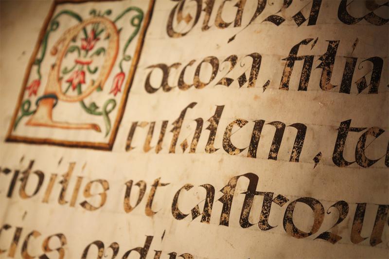 A page of a hand-written medieval manuscript shows ink writing, slightly faded, in old-fashioned letter shapes.