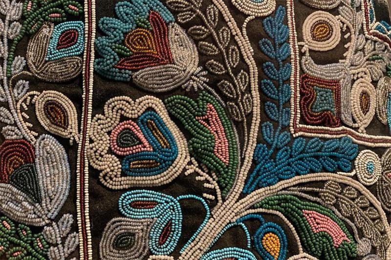 A close-up of miniature beads sewn into an elaborate patterm of leaves and flowers.