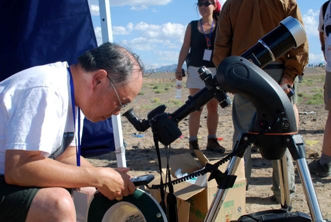 Ralph Choi outside, looking down through a telescope