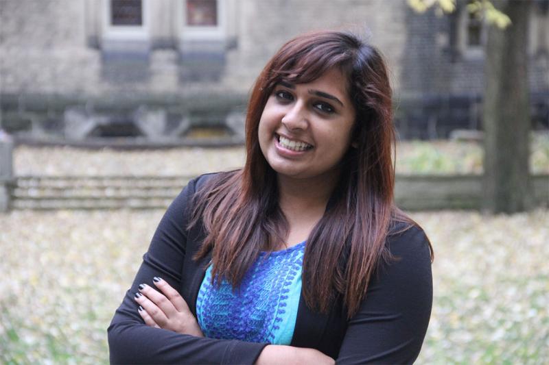 Sarah Qidwai smiles as she stands in a courtyard outdoors.