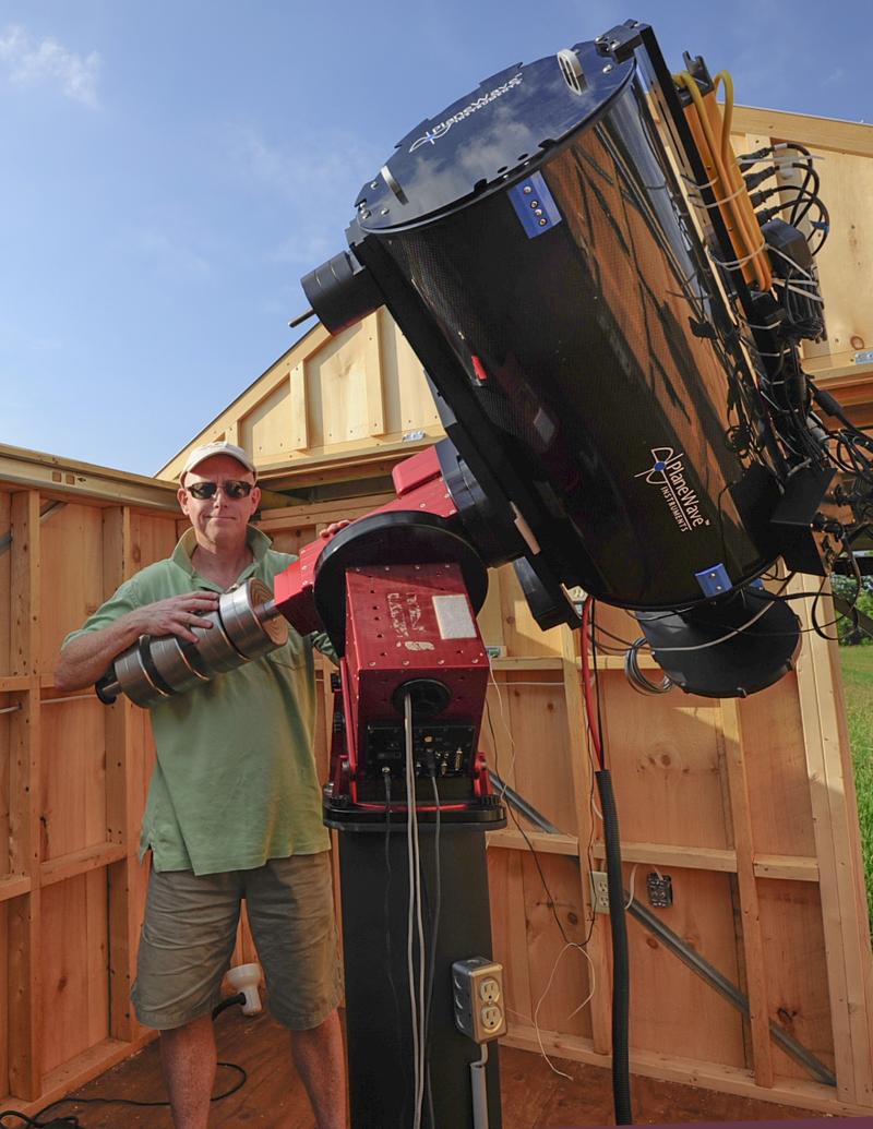 Stuart Heggie stands outside with his telescope.